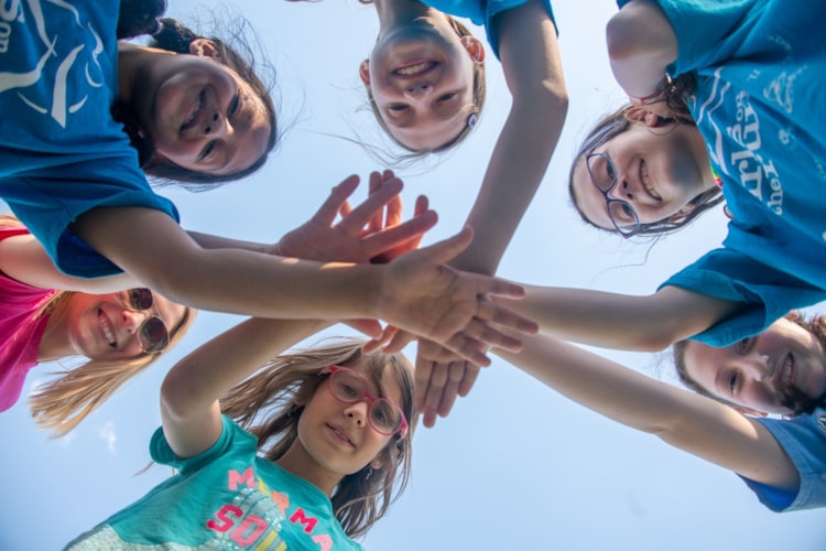 Girls reaching hands in together and smiling 