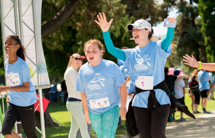 Suzanne and girl in light blue Girls on the Run shirts crossing the finish line